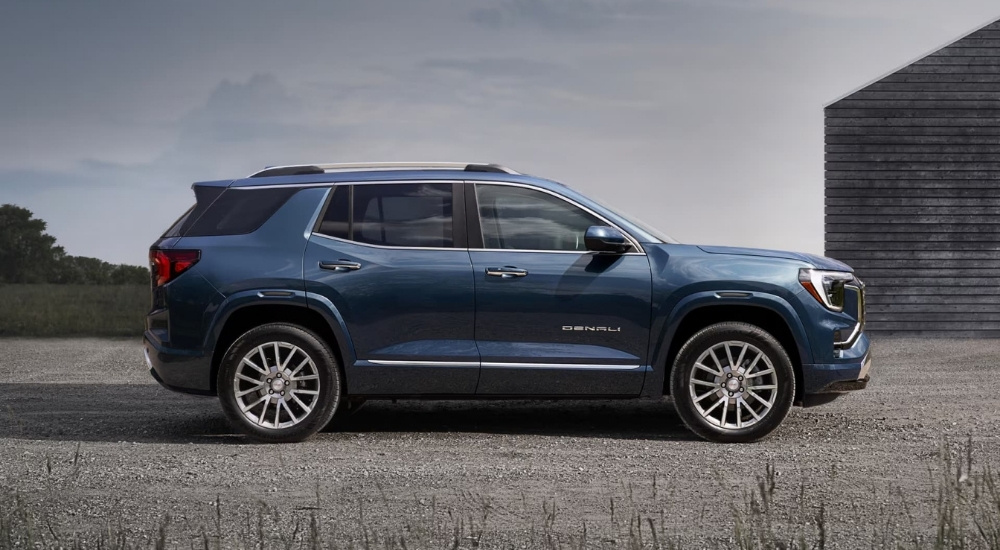 Blue 2026 GMC Terrain Denali is parked near a barn