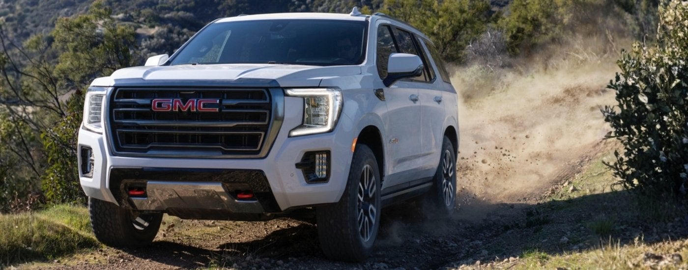 A white 2023 GMC Yukon off-roading on a trail