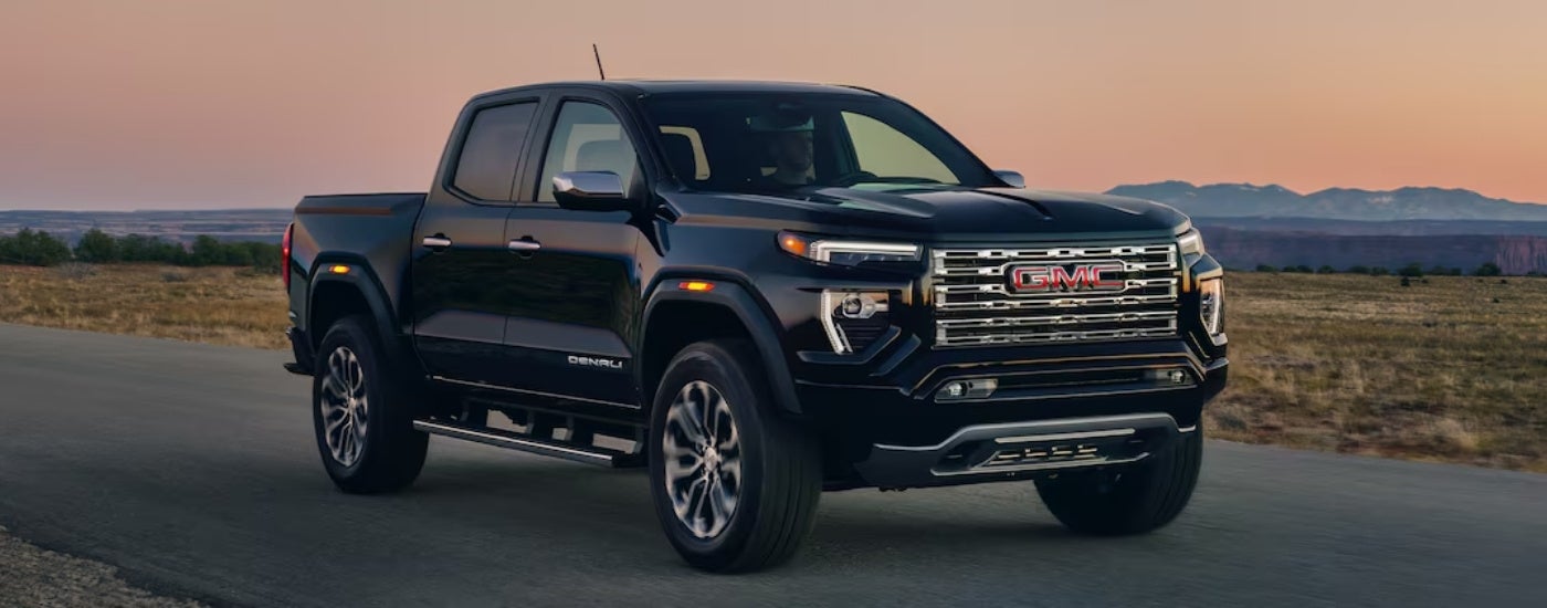 A black 2024 GMC Canyon Denali parked on a backroad.