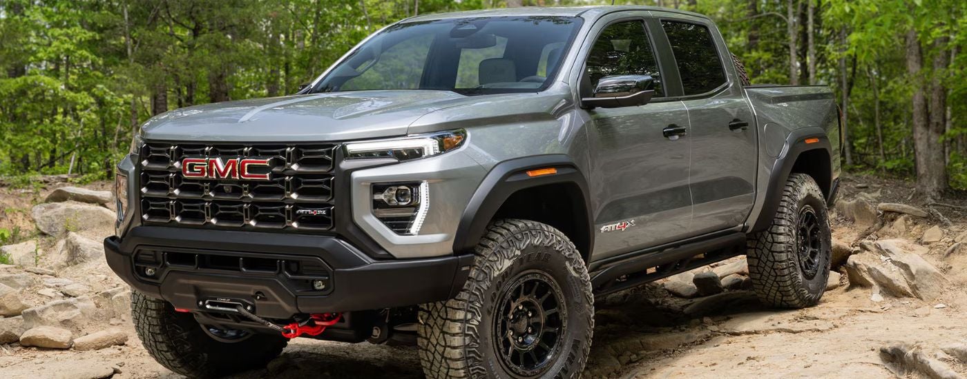Grey 2026 GMC Canyon AT4X driving over rocks.