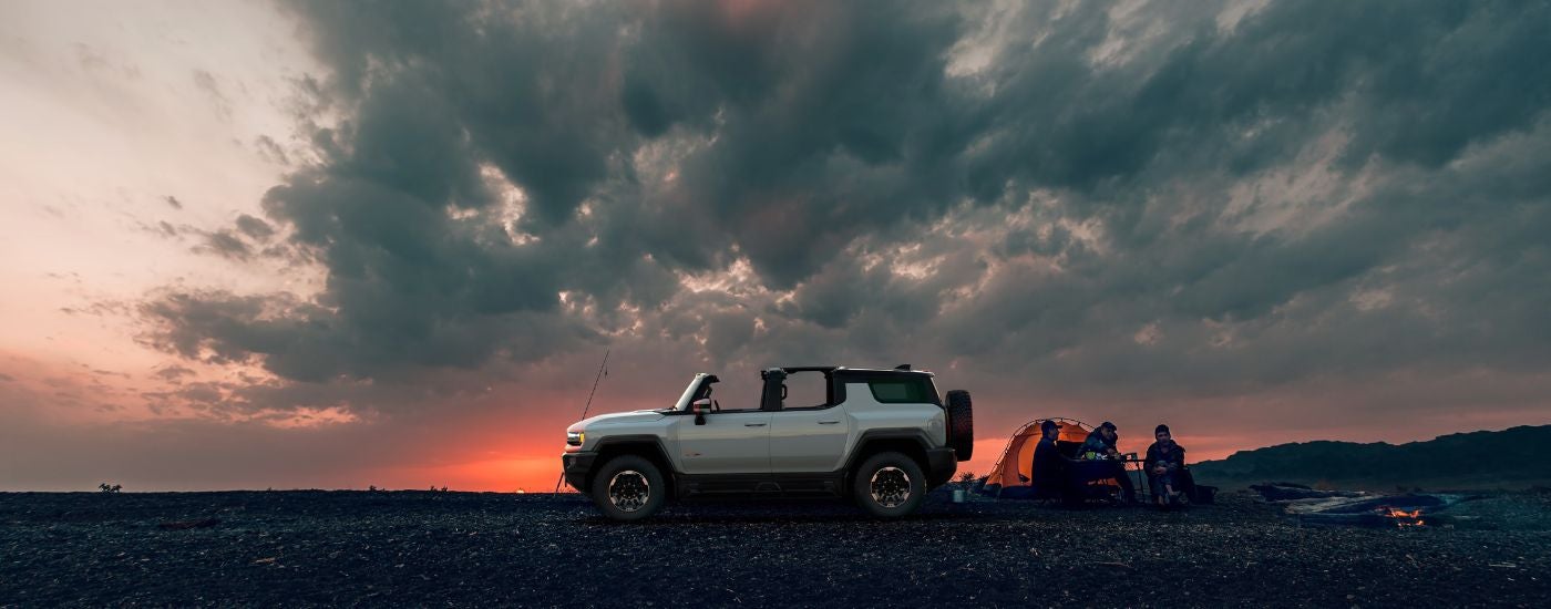 A white 2024 GMC Hummer EV is shown from the side on a cloudy day.